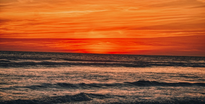 ocean waves crashing on shore during sunset