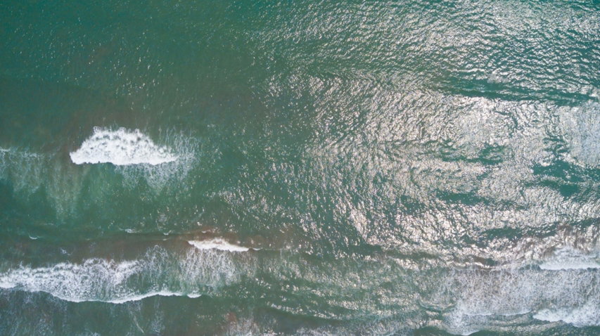 an aerial view of the ocean with waves crashing on the shore